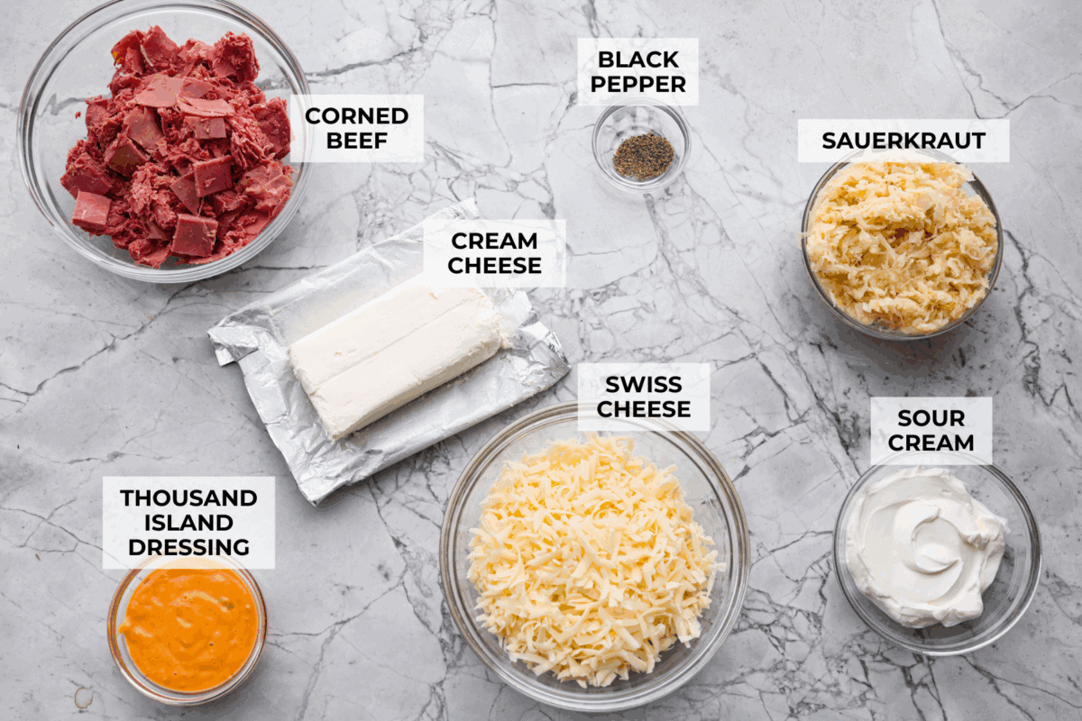 Think of this hot Reuben dip as a love letter to the classic Reuben sandwich. Itโs rich, tangy, loaded with corned beef and sauerkraut, and the perfect way to turn St. Patrickโs Day leftovers into something everyone fights over. Overhead shot of labeled hot reuben dip ingredients.