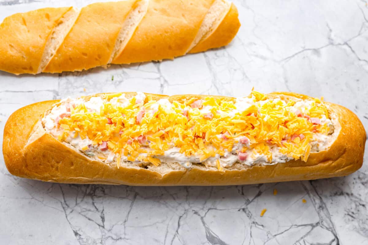 This Mississippi sin dip is pure comfort-food goodness. Creamy, cheesy, a little smoky, and baked into a loaf of French bread, itโs the kind of snack everyone gathers around and keeps going back for! Dip added to the loaf of french bread and then topped with cheese.