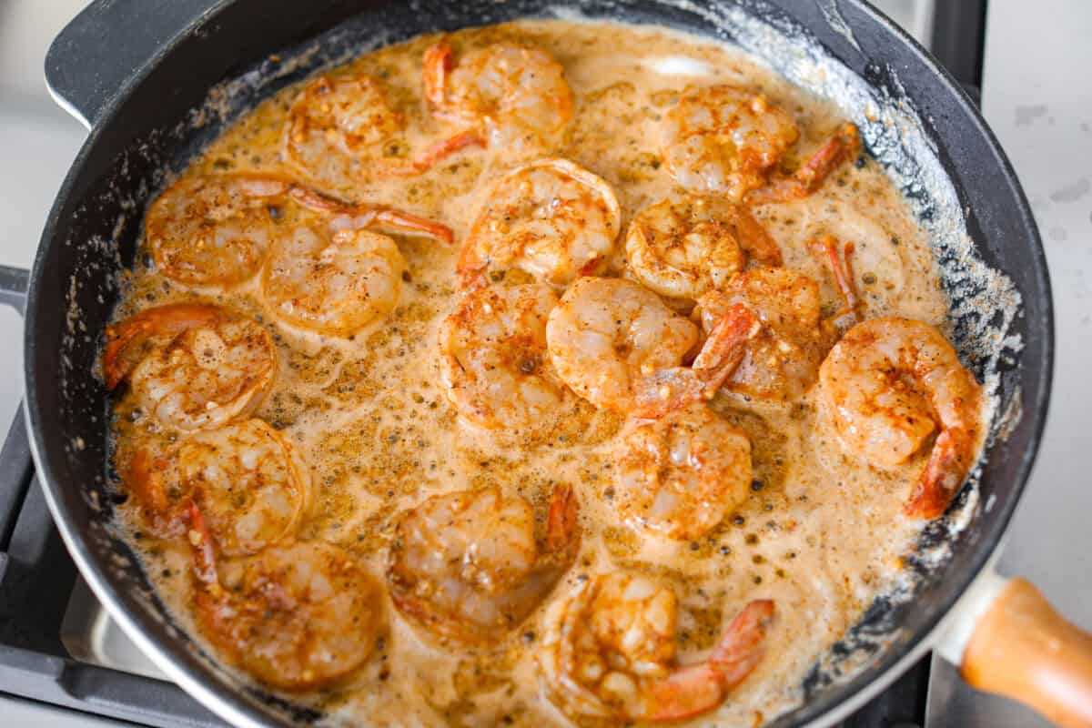 You have to make this New Orleans BBQ shrimp! The shrimp are tender and swimming in a rich, buttery garlic sauce. Grab a bib, lick your fingers, and sop up every last drop with crusty bread. Seasoned shrimp in a skillet with melted butter.