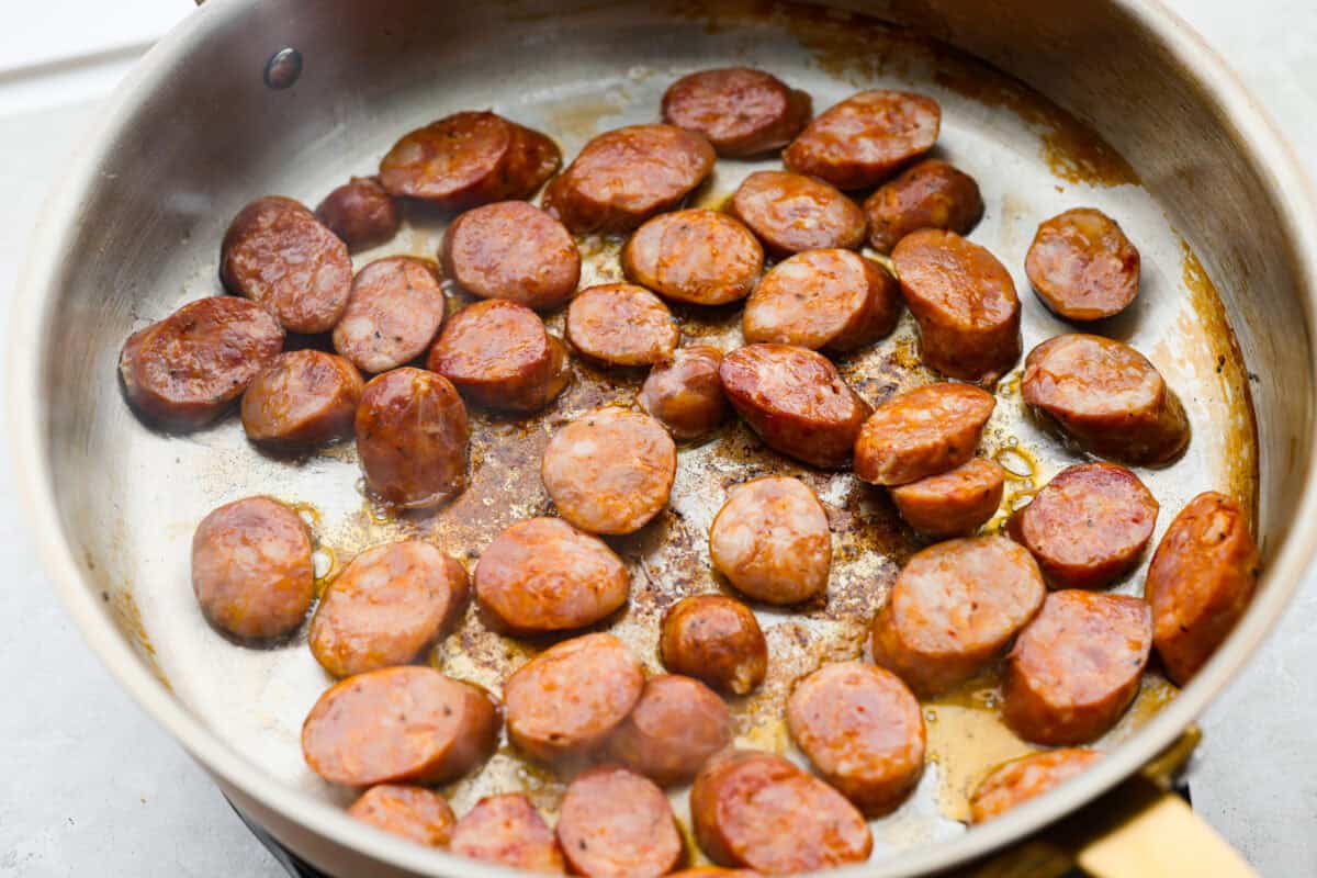 If your family is hungry now and you don't have time to soak beans or babysit the stove, this red beans and rice is for you. It is quick, cozy, and made with canned beans and smoky sausage. It tastes great and is ready fast! Sausage browning in a skillet.