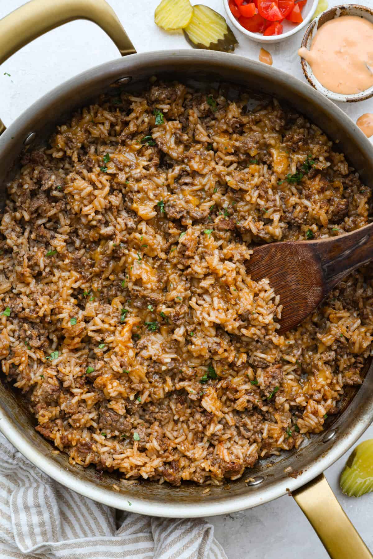 Cheeseburger rice is everything you love about a juicy cheeseburger, made easy in one skillet. Hearty, cheesy, and packed with flavor, itโs the ultimate weeknight comfort meal. Skillet of cheeseburger rice with a wooden spoon.