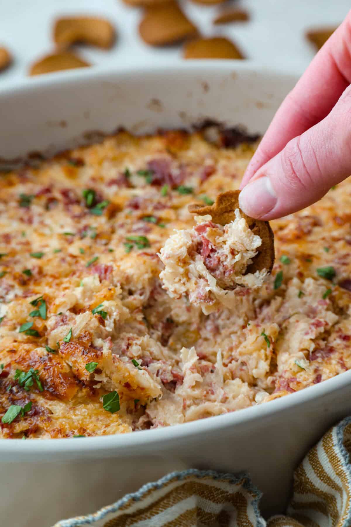 Think of this hot Reuben dip as a love letter to the classic Reuben sandwich. Itโs rich, tangy, loaded with corned beef and sauerkraut, and the perfect way to turn St. Patrickโs Day leftovers into something everyone fights over. Someone scooping a bite of hot Reuben dip.