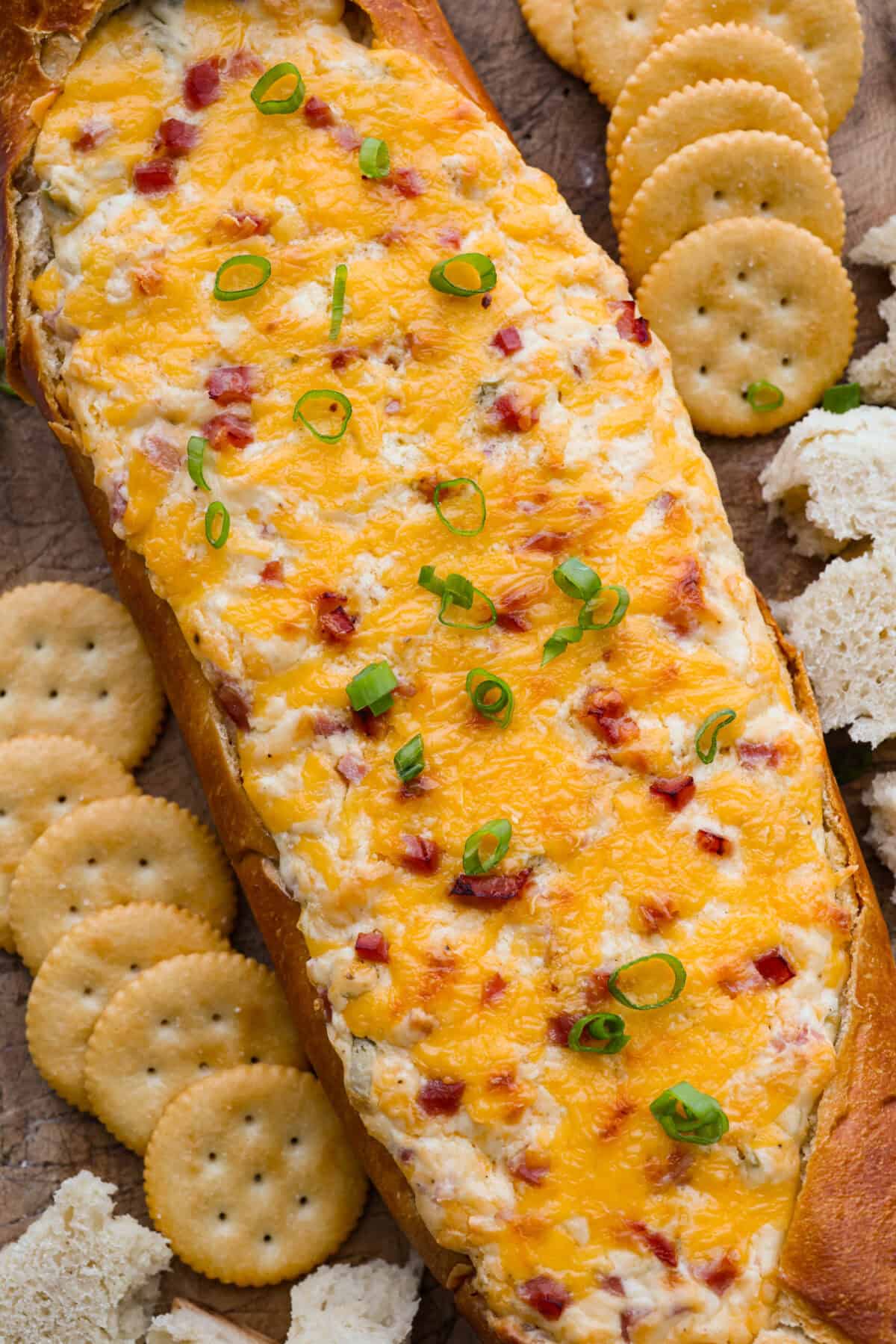 This Mississippi sin dip is pure comfort-food goodness. Creamy, cheesy, a little smoky, and baked into a loaf of French bread, itโs the kind of snack everyone gathers around and keeps going back for! Overhead shot of Mississippi sin dip surrounded by crackers.