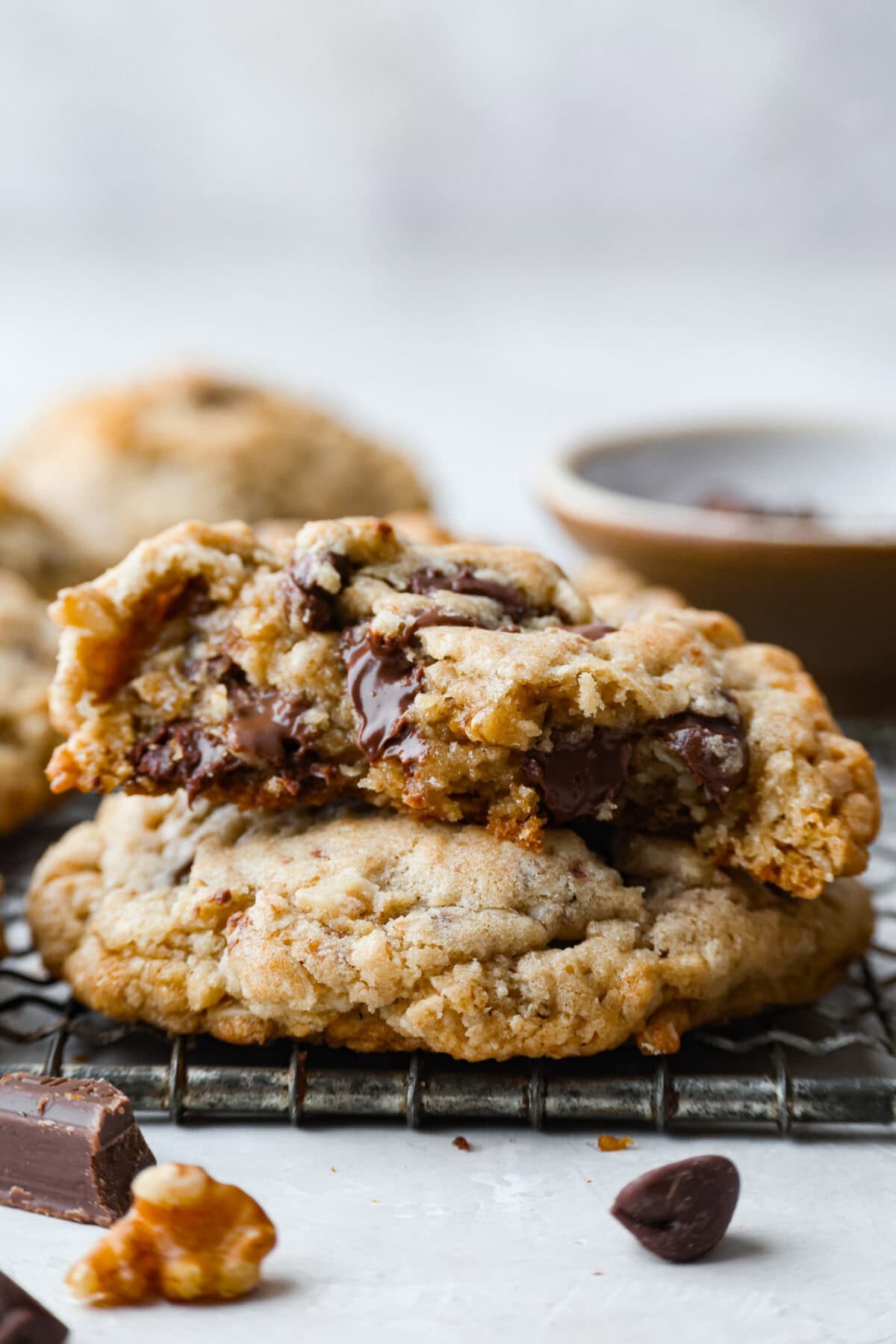 These Neiman Marcus Chocolate Chip Cookies come with a famous backstory, but the real star is the cookie itself. Thick, chewy, and packed with oats, two kinds of chocolate, and crunchy walnuts, theyโre truly worth the hype. Side shot of stacked Neiman Marcus chocolate chip cookies, where the top on is cut in half and soft chocloate is melting over.