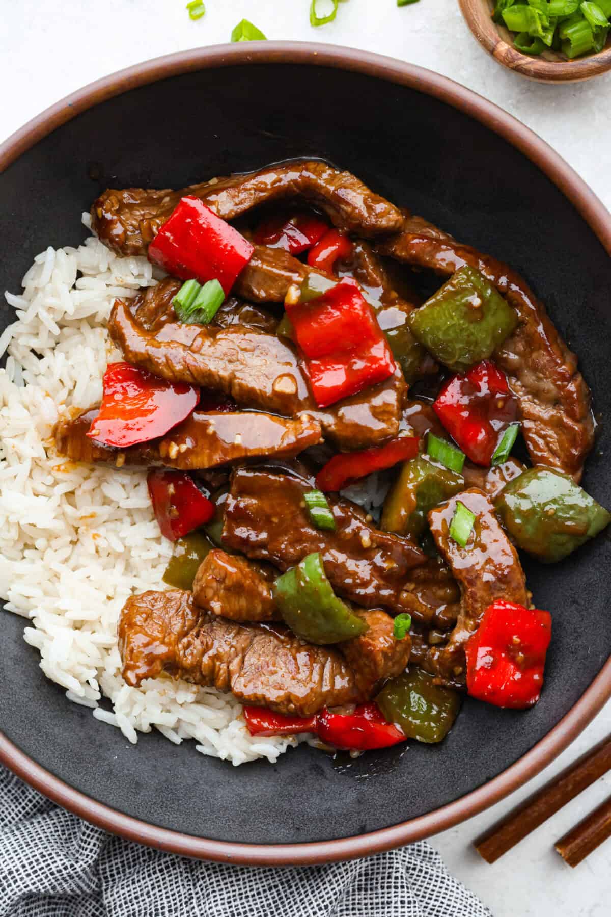 Trust me on this one. If you want the most tender pepper steak you’ve ever made at home, this recipe is it. It’s fast, saucy, and I give you just enough tips to make it work on a busy night! Plated serving of pepper steak over a bed of white rice.