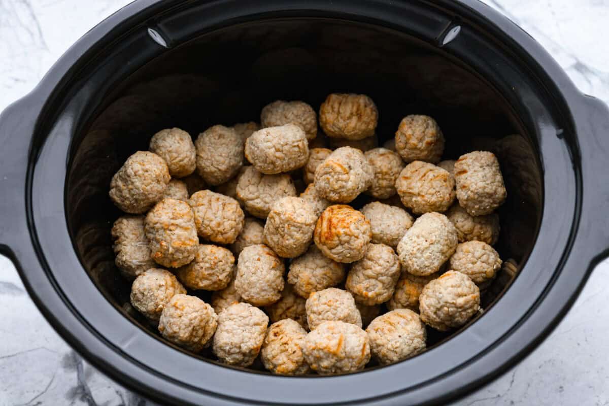 Slow cooker bourbon meatballs are an easy, set-it-and-forget-it favorite. Frozen meatballs simmer in a sweet, sticky bourbon sauce, making them perfect for an appetizer or a simple dinner with just 10 minutes of prep. Frozen meatballs added to the bottom of the crockpot.