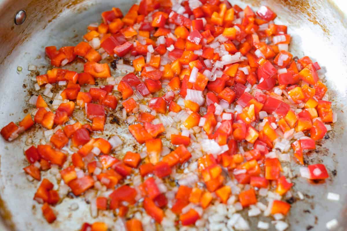 This Cajun spaghetti is comforting like classic spaghetti but delivers a bold Cajun kick with sausage and a creamy sauce. You'll have a super flavorful dinner your whole family will love in no time! Veggies cooking in a pan.