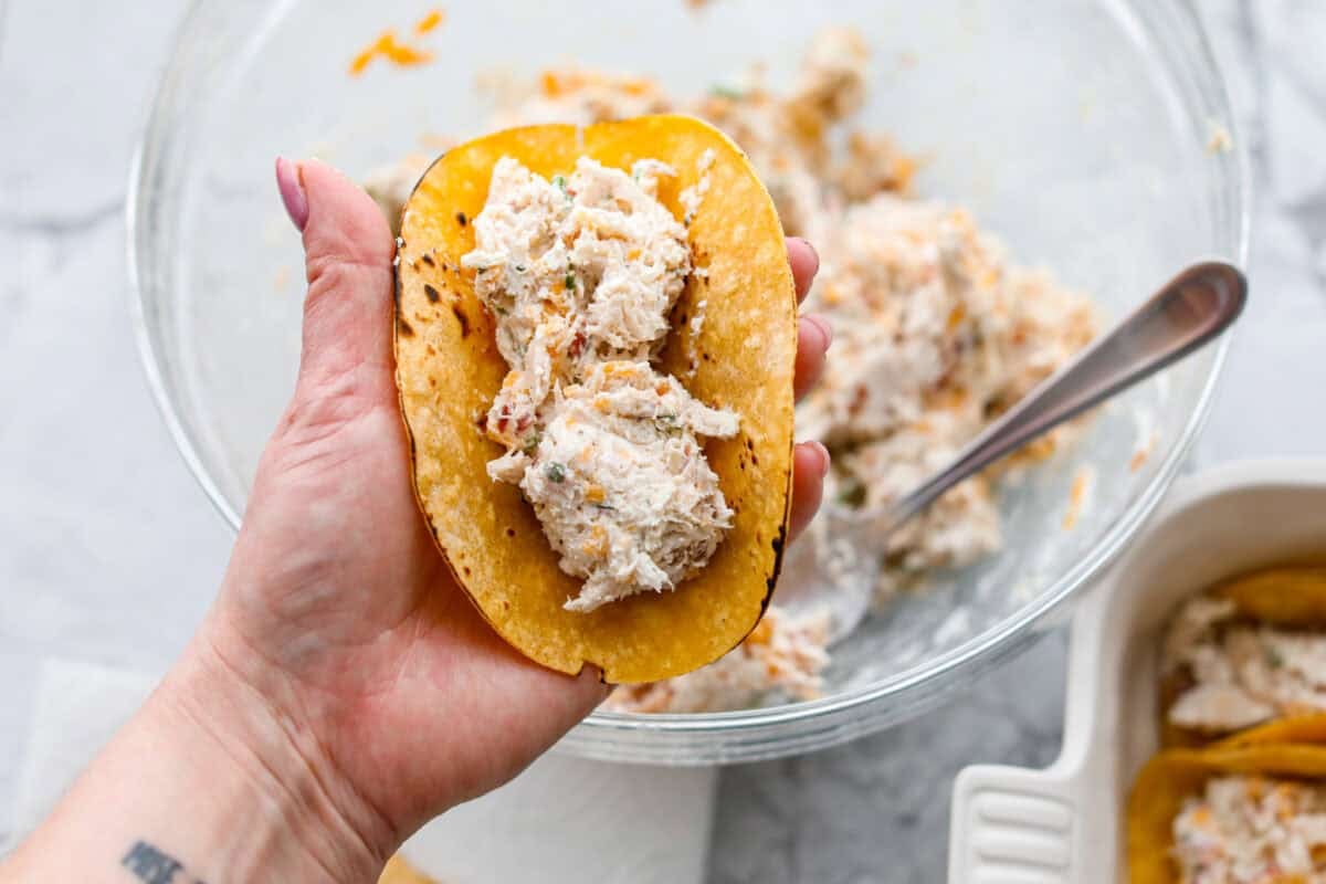 Get ready to be instantly obsessed with these crack chicken tacos! They are loaded with creamy ranch chicken, crispy bacon, and melty cheddar for a can’t-stop-eating dinner that disappears fast. Someone filling the tortillas with crack chicken mixture.