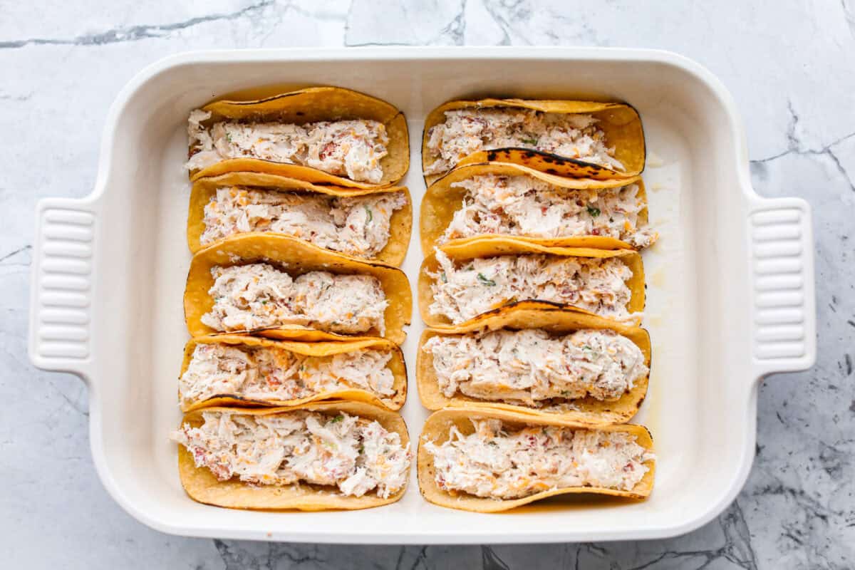 Get ready to be instantly obsessed with these crack chicken tacos! They are loaded with creamy ranch chicken, crispy bacon, and melty cheddar for a can’t-stop-eating dinner that disappears fast. Tacos all lines up in the baking dish ready to be baked.