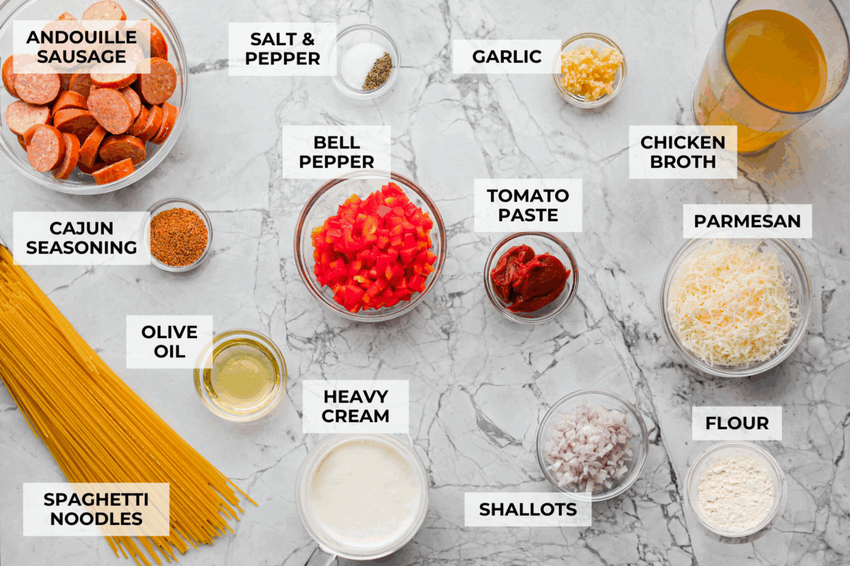 This Cajun spaghetti is comforting like classic spaghetti but delivers a bold Cajun kick with sausage and a creamy sauce. You'll have a super flavorful dinner your whole family will love in no time! Overhead shot of labeled Cajun Spaghetti ingredients.