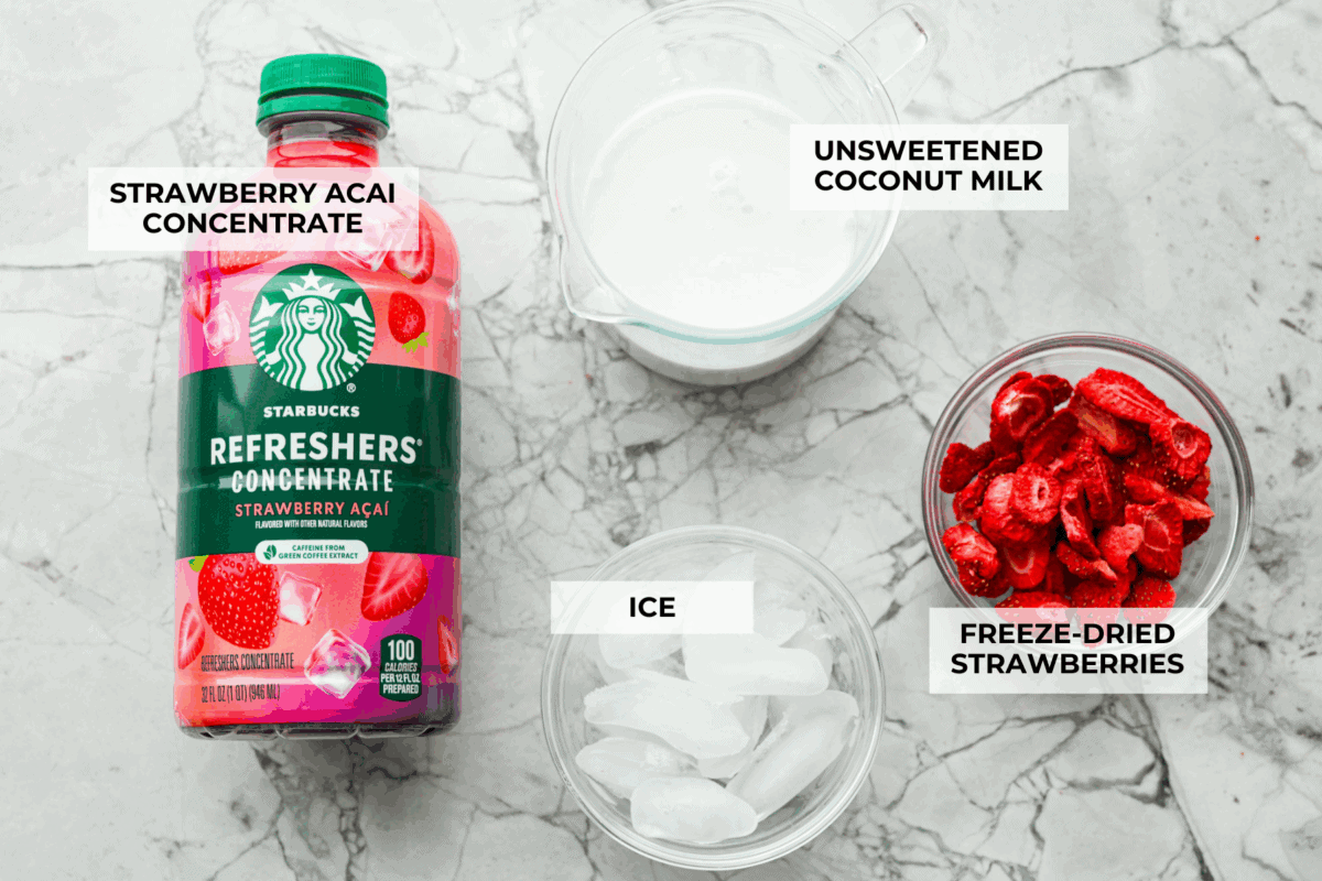 You guys, Starbucks sells the Strawberry Aรงaรญ concentrate in stores! Which means we can make the famous Starbuck's Pink Drink at home! And let me tell you, it's spot on! With just three ingredients, it's ridiculously easy to make year-round, and so good! Overhead shot of labeled ingredients.