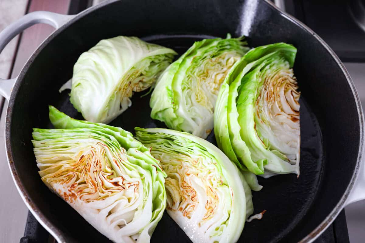 Groceries are expensive right now, so Iโve been leaning hard on the cheap staples. This melting cabbage with a garlicky cream sauce, sun-dried tomatoes, and Parmesan is easy, budget friendly, and tastes amazing. Cabbage wedges browning in a skillet.