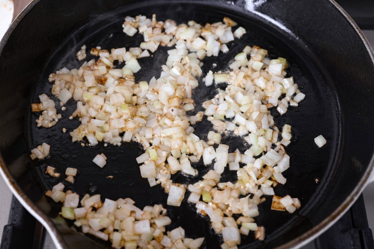 Groceries are expensive right now, so Iโve been leaning hard on the cheap staples. This melting cabbage with a garlicky cream sauce, sun-dried tomatoes, and Parmesan is easy, budget friendly, and tastes amazing. Onions cooking in a skillet.