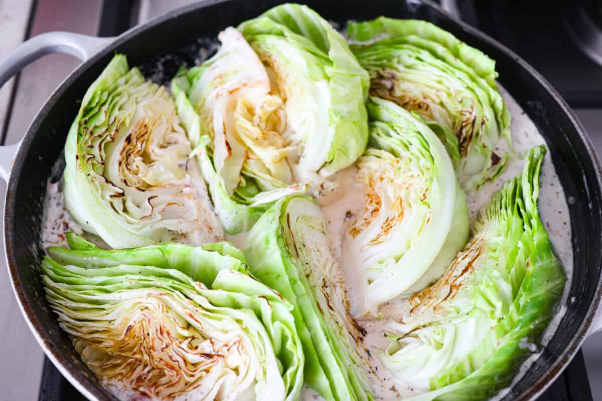 Groceries are expensive right now, so Iโve been leaning hard on the cheap staples. This melting cabbage with a garlicky cream sauce, sun-dried tomatoes, and Parmesan is easy, budget friendly, and tastes amazing. Cabbage wedges added back to the skillet.