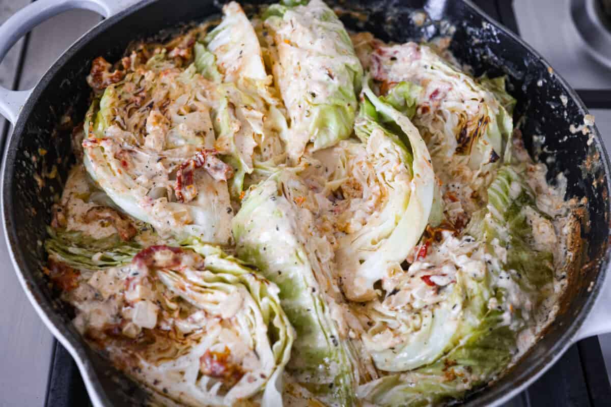 Groceries are expensive right now, so Iโve been leaning hard on the cheap staples. This melting cabbage with a garlicky cream sauce, sun-dried tomatoes, and Parmesan is easy, budget friendly, and tastes amazing. Cabbage wedges ready to be covered and placed in the oven to bake.