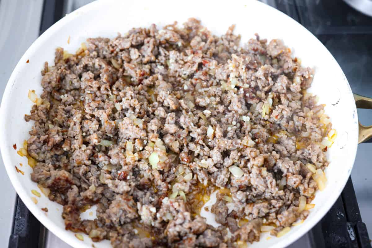 My classic manicotti is a reader favorite, so I wanted to make a version with a little more protein. Sausage is one of my favorite pasta add-ins, and it keeps this new Sausage Manicotti budget-friendly, hearty, cheesy, and so satisfying. Sausage and onions cooked in a skillet.