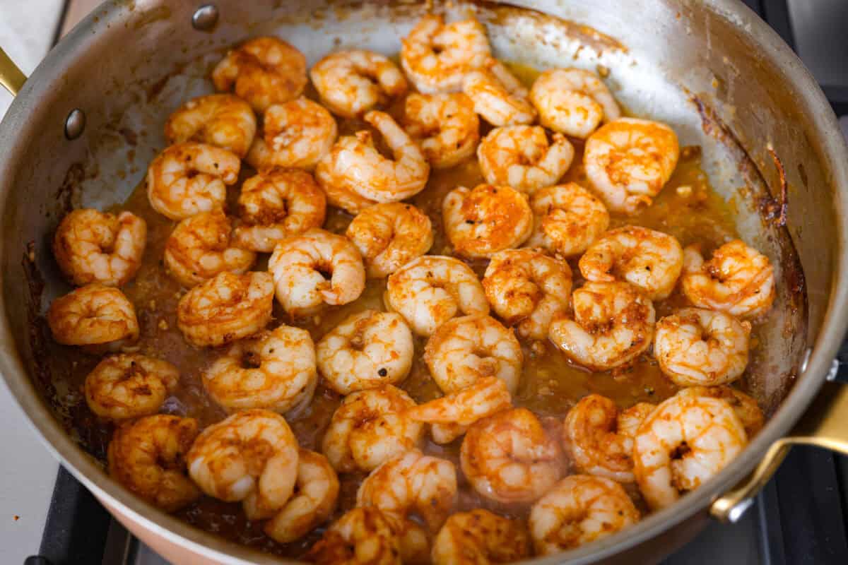 Bang bang shrimp pasta is what weeknight dinner dreams are made of! Juicy shrimp, tender pasta, and that irresistible sweet-and-spicy bang bang sauce come together in just 20 minutes. It’s creamy, bold, and guaranteed to be a hit. Shrimp cooking in a skillet.