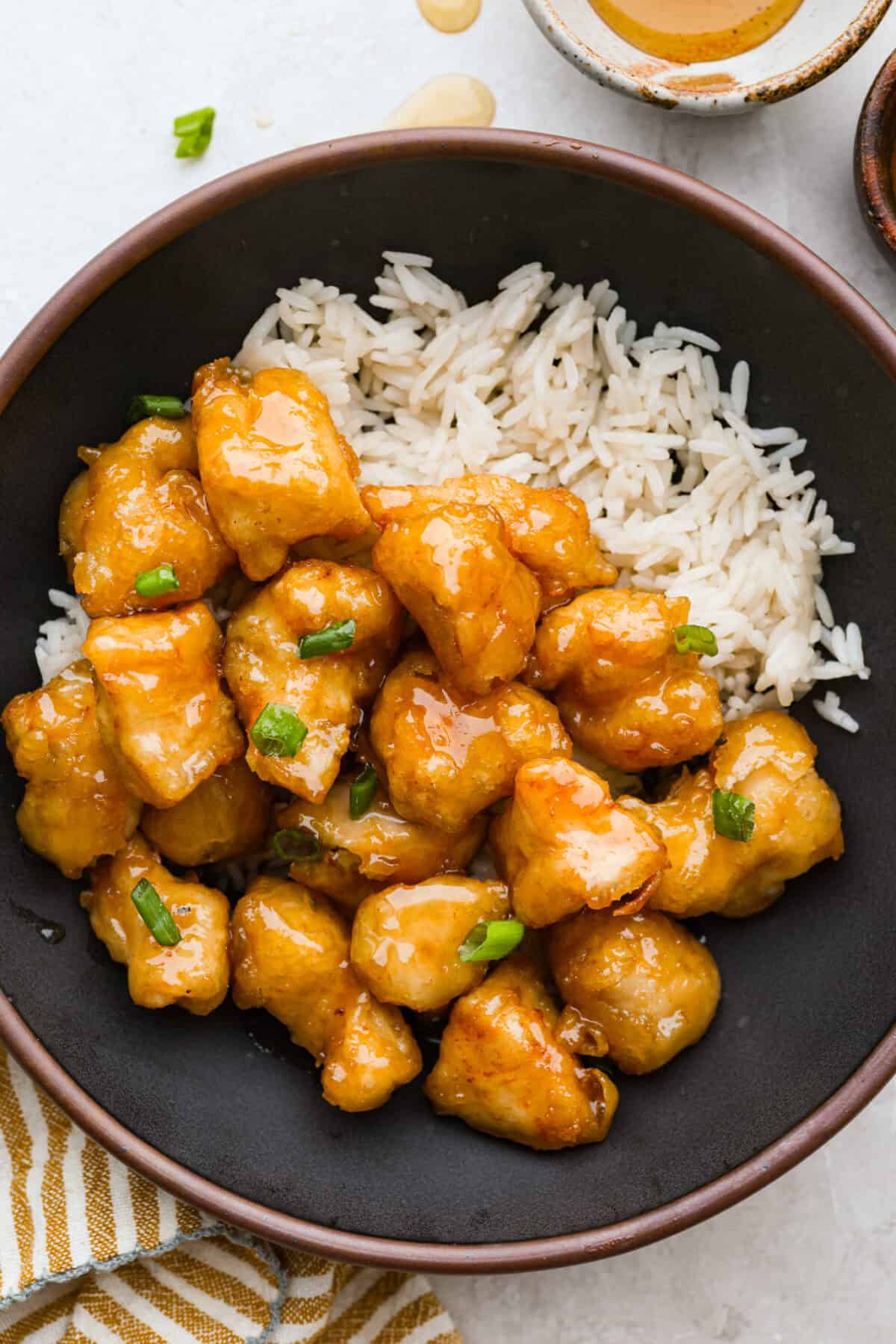 Skip takeout and make this PF Chang’s honey chicken in your own kitchen! Crispy fried chicken gets coated in a glossy honey sauce that’s sweet, savory, and hard to resist Bowl of PF Chang's honey chicken on a bed of rice.