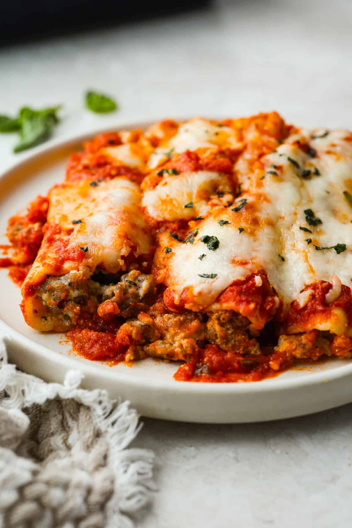 My classic manicotti is a reader favorite, so I wanted to make a version with a little more protein. Sausage is one of my favorite pasta add-ins, and it keeps this new Sausage Manicotti budget-friendly, hearty, cheesy, and so satisfying. Plated sausage manicotti covered in melty cheese.