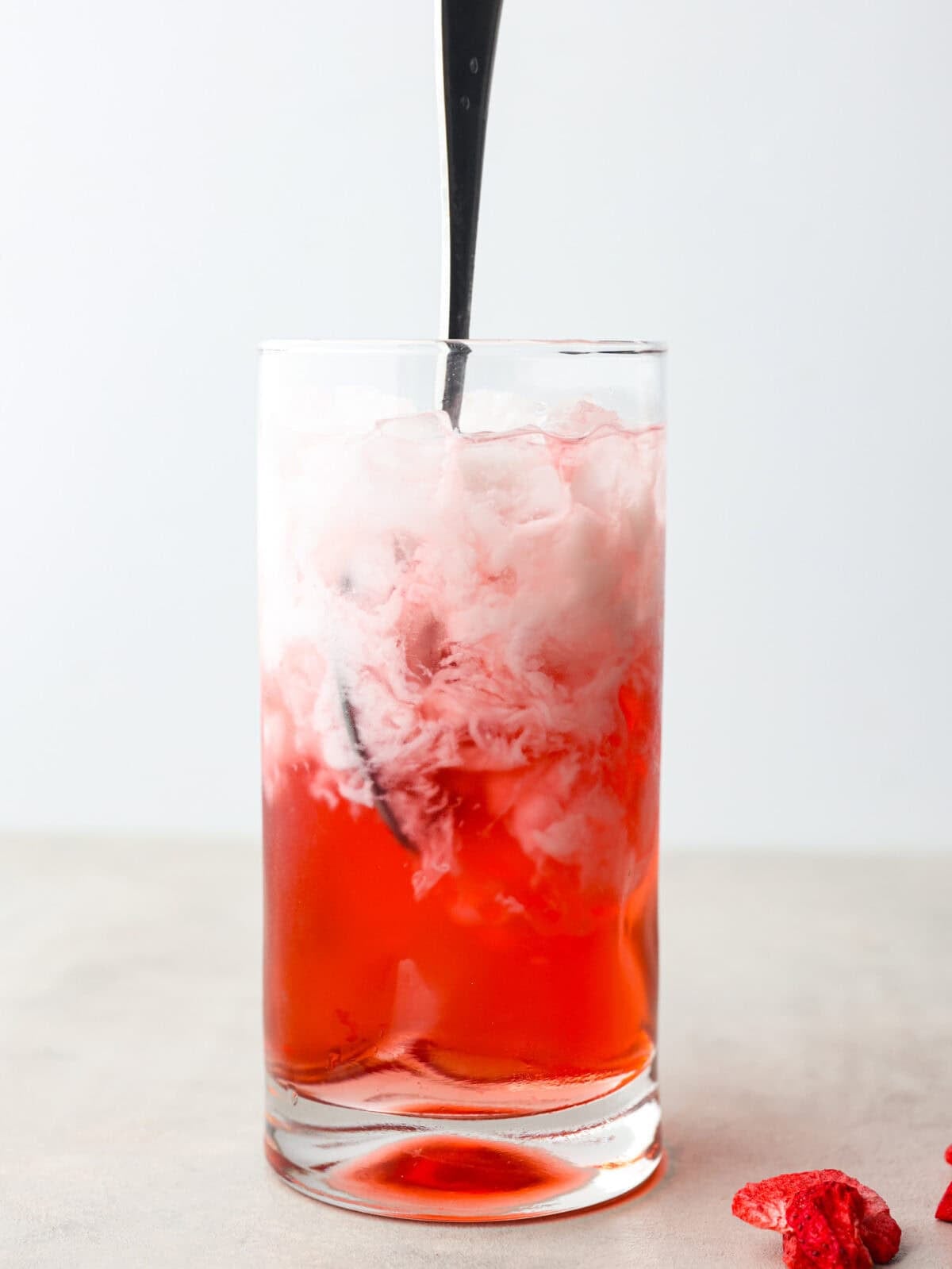 You guys, Starbucks sells the Strawberry Aรงaรญ concentrate in stores! Which means we can make the famous Starbuck's Pink Drink at home! And let me tell you, it's spot on! With just three ingredients, it's ridiculously easy to make year-round, and so good! Someone stirring the ingredients together.