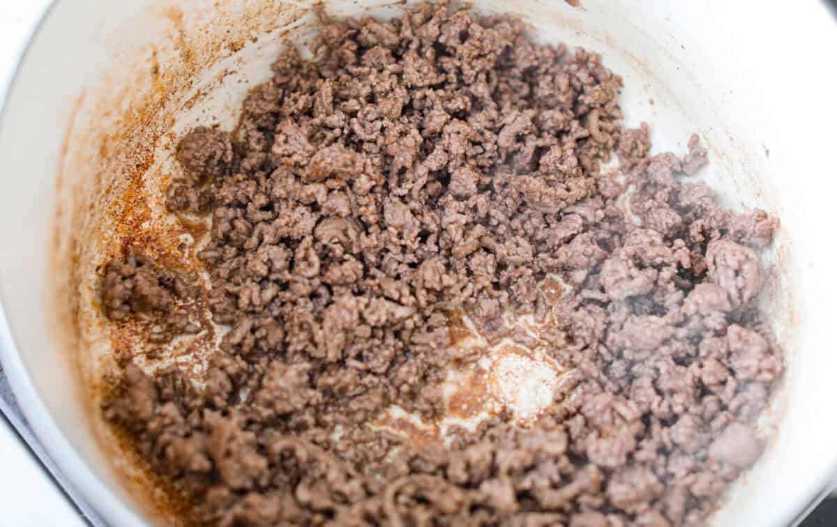 If you're bringing a dish to the cookout, make it these loaded baked beans. Three kinds of meat, two kinds of beans, and a sauce that is smoky, sweet, and full of depth. They disappear every single time. Ground beef cooking in a a large pot.