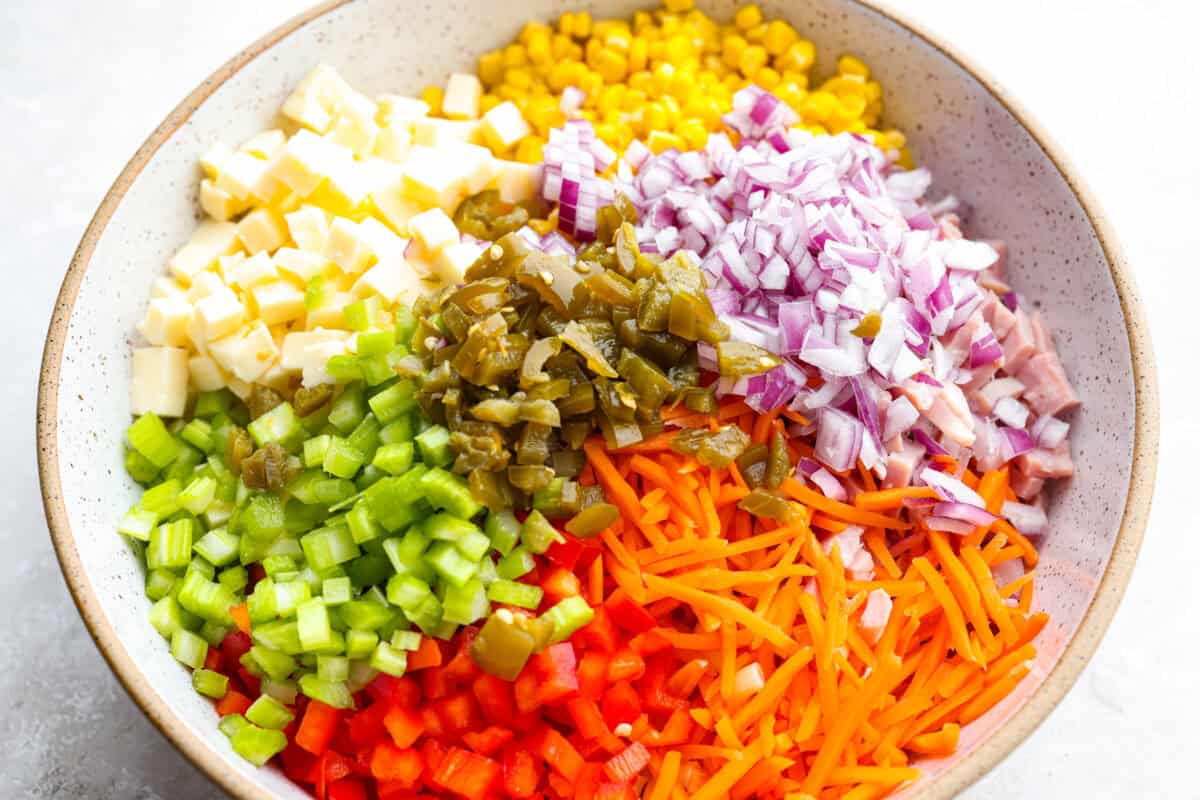 This Mexican macaroni salad is a fun twist on a classic! Itโs creamy, tangy, and full of flavor with crisp veggies, cheese, and a little kick from jalapeรฑos. Perfect for BBQs, potlucks, or anytime you want an easy, delicious side. All of the cheese, veggies and other ingredients in a bowl that go in the salad.