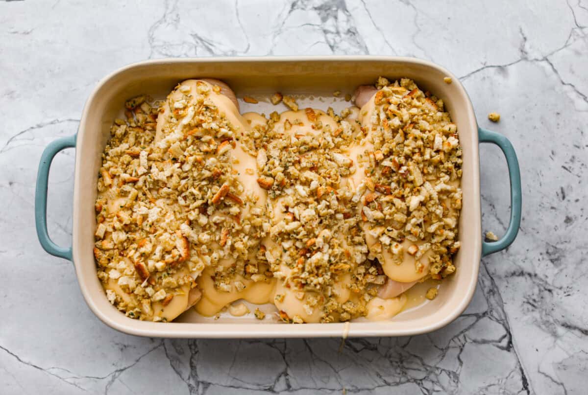 Okay, this Swiss Chicken Casserole is my go-to when I donโt feel like cooking. You basically throw it together, pop it in the oven, and somehow end up with super tender chicken, melty Swiss cheese, and the creamiest sauce. Stuffing mix added to the top of the chicken, ready to go in to oven.