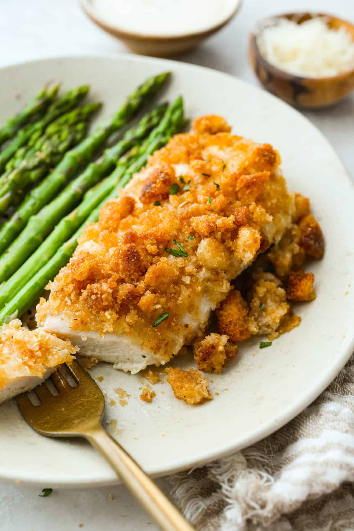 My Caesar chicken bakeย turns classic Caesar salad flavors into an easy one-pan dinner! Juicy chicken is smothered in creamy dressing, topped with parmesan and buttery crushed croutons, and baked to golden, cheesy perfection. Plated caesar chicken salad bake with asparagus.