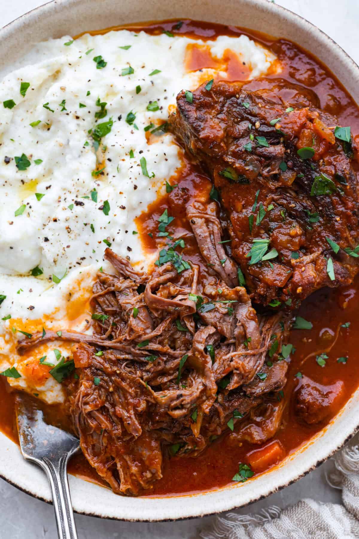 Plated Italian Pot Roast next to some polenta. 