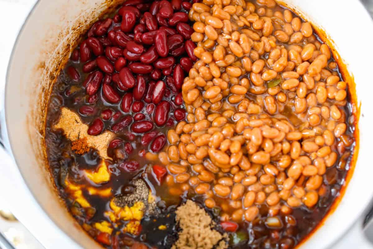 If you're bringing a dish to the cookout, make it these loaded baked beans. Three kinds of meat, two kinds of beans, and a sauce that is smoky, sweet, and full of depth. They disappear every single time. Beans and sauce ingredients added to the pot.