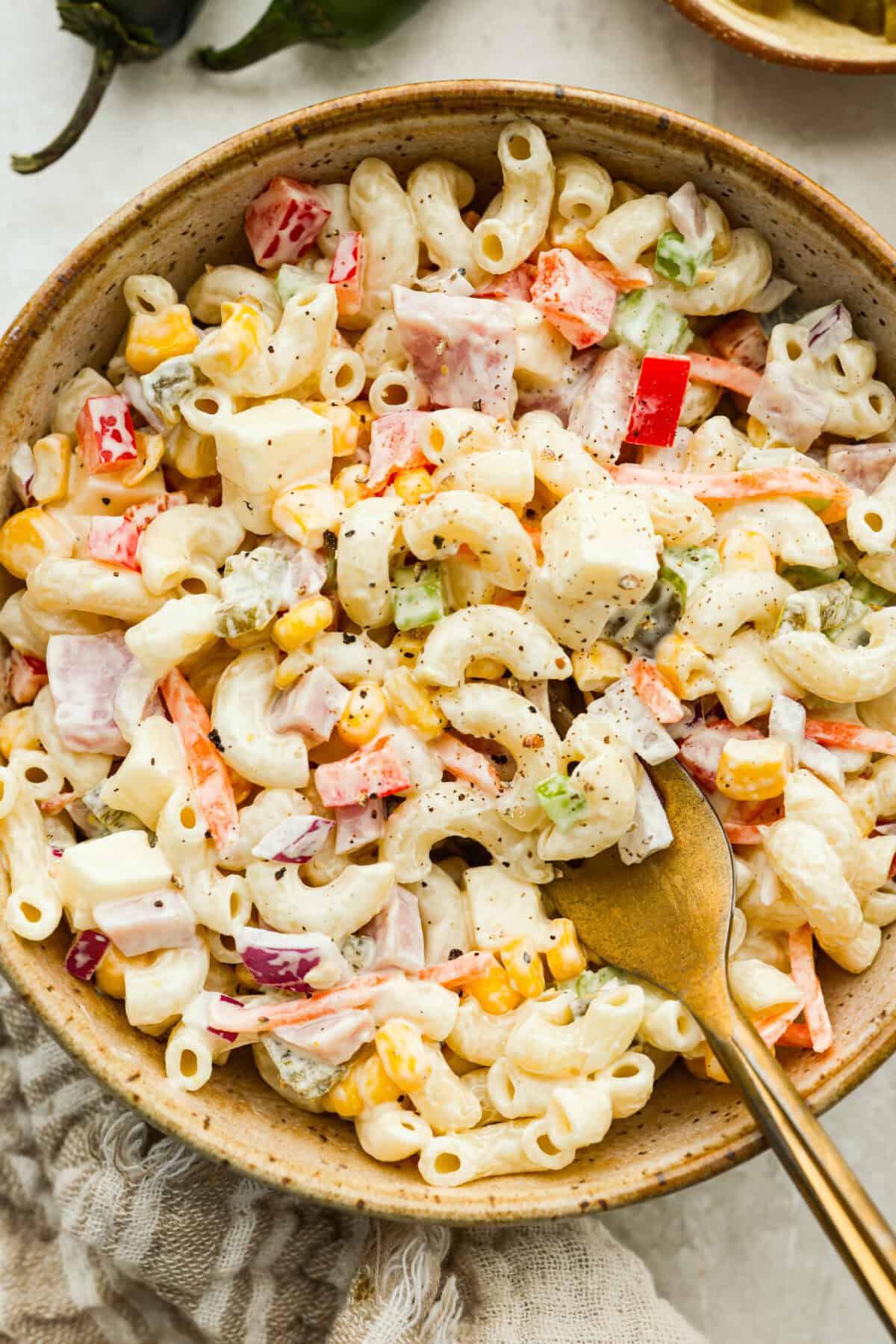 This Mexican macaroni salad is a fun twist on a classic! Itโs creamy, tangy, and full of flavor with crisp veggies, cheese, and a little kick from jalapeรฑos. Perfect for BBQs, potlucks, or anytime you want an easy, delicious side. Serving of Mexican macaroni salad in a bowl with a gold fork.