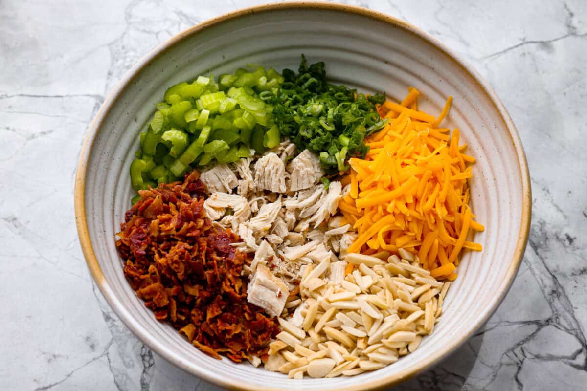 Million dollar chicken salad totally lives up to the name. Itโs creamy, cheesy, crunchy, and packed with bacon, so every bite is full of flavor. Serve it on croissants, with crackers, or straight from the bowl! It's that good. Chicken, bacon, celery, green onions, cheese and almonds all added to a bowl.