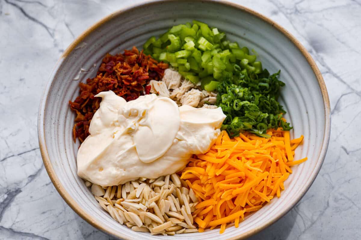 Million dollar chicken salad totally lives up to the name. Itโs creamy, cheesy, crunchy, and packed with bacon, so every bite is full of flavor. Serve it on croissants, with crackers, or straight from the bowl! It's that good. Mayonnaise added to the bowl of ingredients.