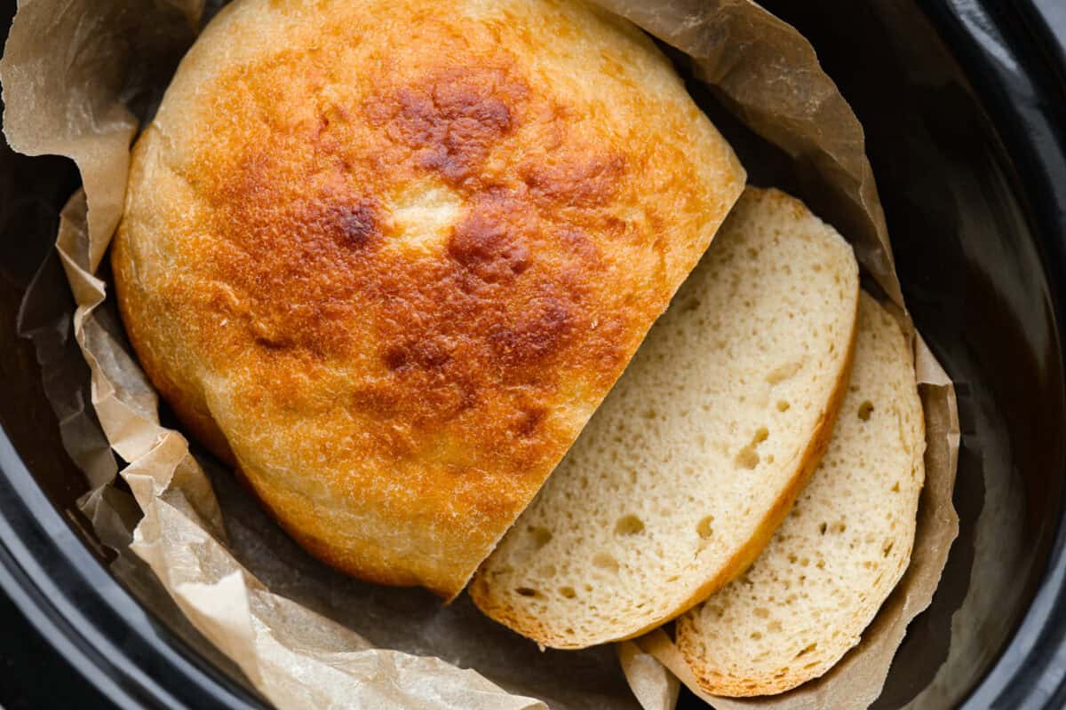 If you’ve ever wanted homemade bread without all the work, this slow cooker bread is my favorite easy trick. As a busy mom, I love that a few simple ingredients and my slow cooker turn into a warm, soft loaf with hardly any effort. Browned slow cooker bread sliced and placed back in the corckpot.