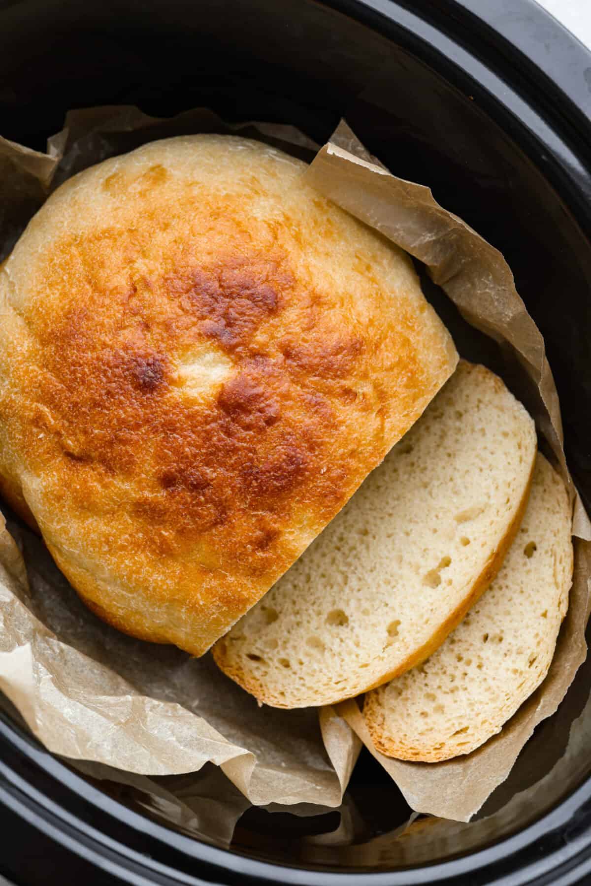 If you’ve ever wanted homemade bread without all the work, this slow cooker bread is my favorite easy trick. As a busy mom, I love that a few simple ingredients and my slow cooker turn into a warm, soft loaf with hardly any effort. Slow cooker bread inside of the slow cooker on the parchment paper.