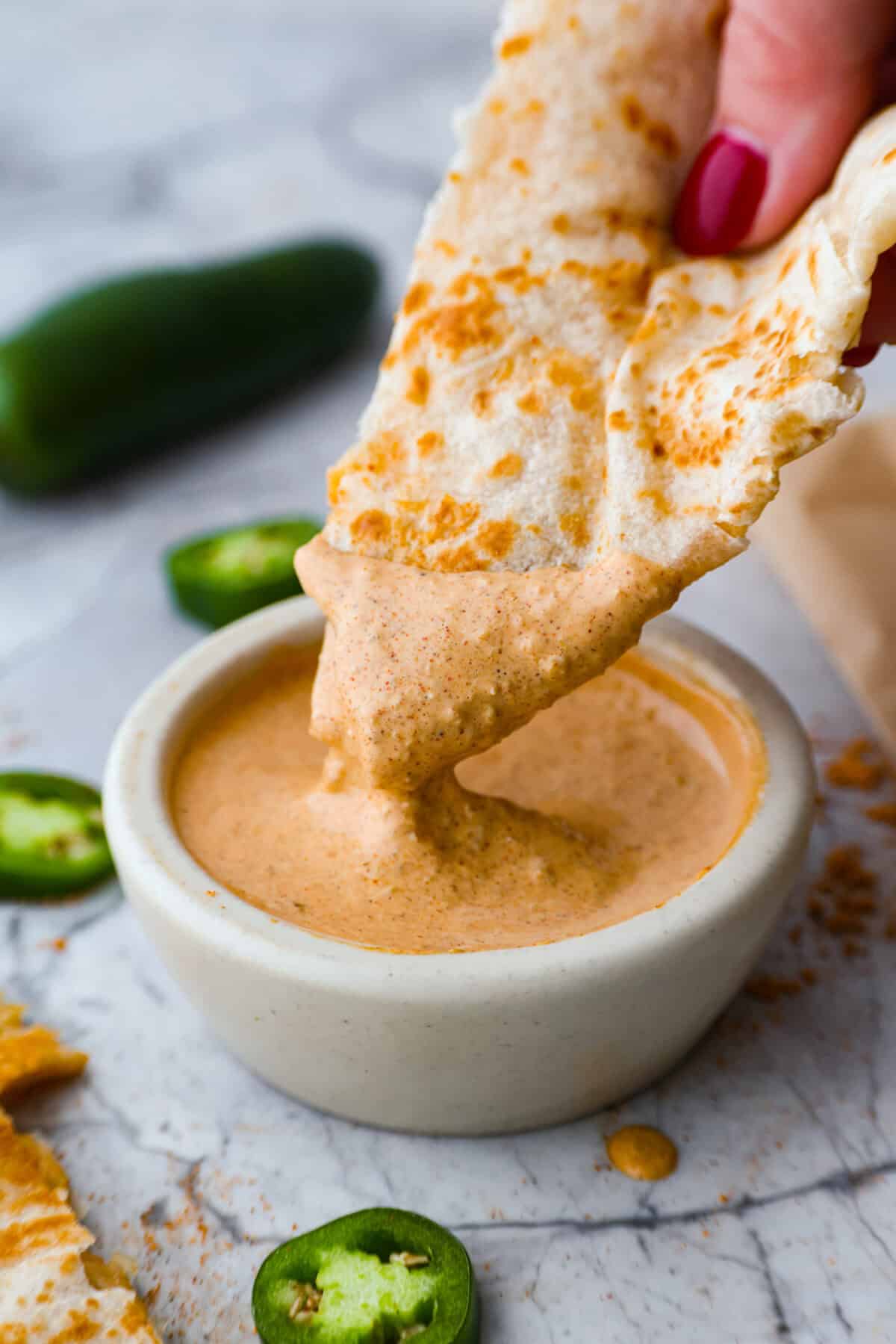 Serve: Enjoy with fresh quesadillas or use as a dipping sauce for your favorite Tex-Mex meals.ย I love this sauce drizzled over chicken burrito bowls! Someone dipping a quesadilla into the Taco Bell quesadilla sauce.