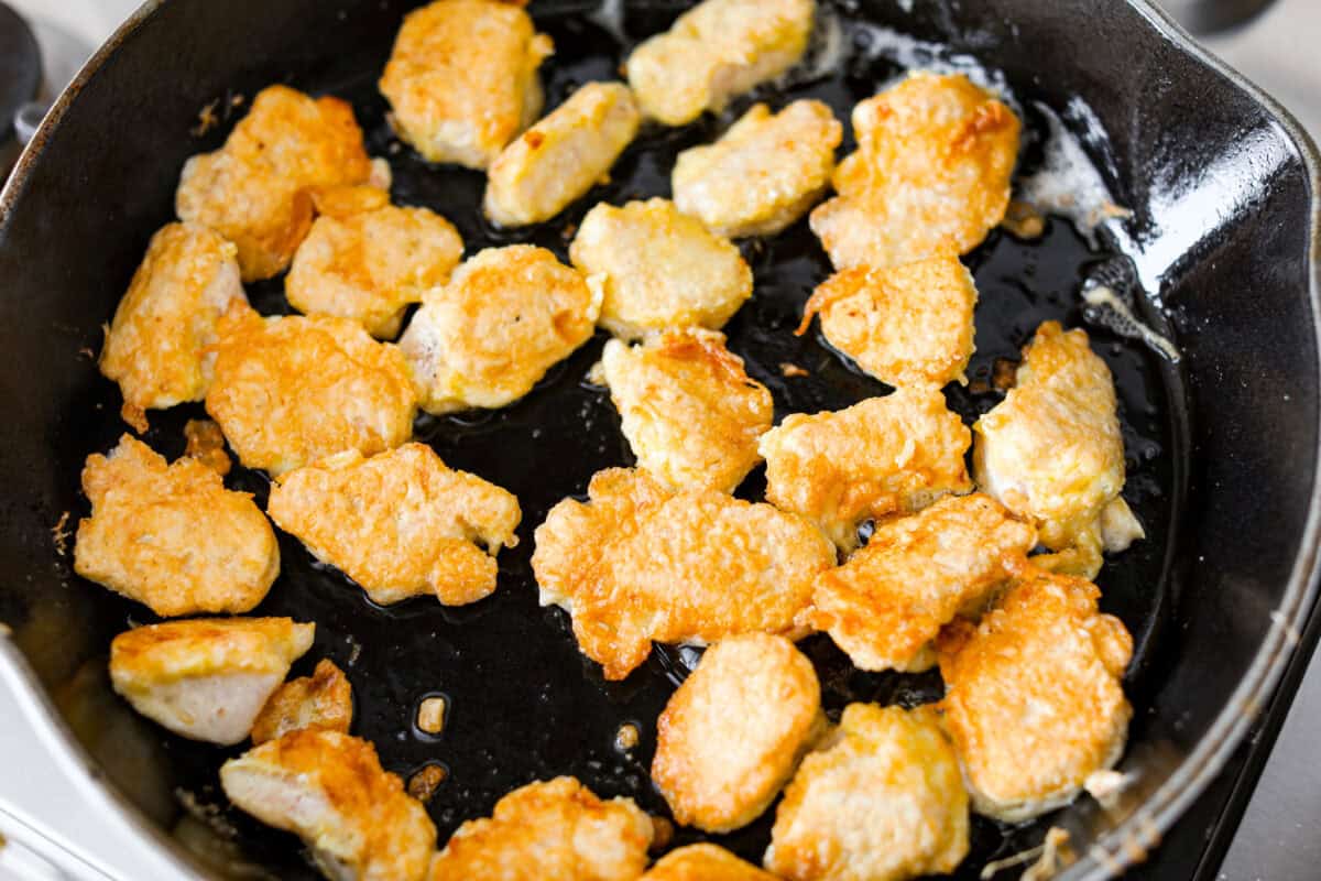I'm updating my "Tuesday night dinner that feels like we're in Hawaii" with double the sauce! You guys asked, so I added more of that sweet, tangy, deliciousness to this Baked Sweet Hawaiian chicken! It's easy, even after a busy day! Coated chicken browning in a skillet.