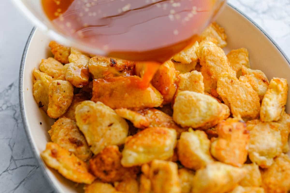 I'm updating my "Tuesday night dinner that feels like we're in Hawaii" with double the sauce! You guys asked, so I added more of that sweet, tangy, deliciousness to this Baked Sweet Hawaiian chicken! It's easy, even after a busy day! Sauce being poured over the chicken