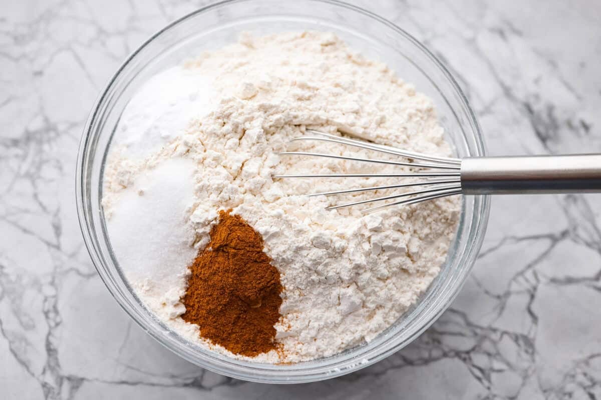 If you’ve never had hummingbird cake, just know it’s one of those cakes people take a bite of and immediately ask for the recipe. It’s soft, sweet, packed with banana and pineapple, and topped with a cream cheese frosting that is to die for! Dry ingredients added to a mixing bowl, ready to be whisked together.