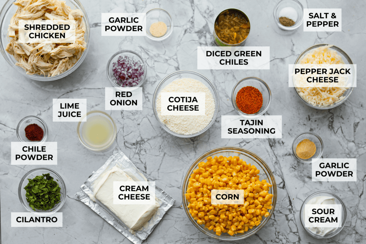 This Mexican Street Corn Chicken Casserole takes everything you love about elote, tangy lime, smoky Tajin, and creamy cotija, and turns it into one bubbly, cheesy weeknight dinner the whole family will devour! Overhead shot of labeled Mexican street corn chicken casserole ingredients.