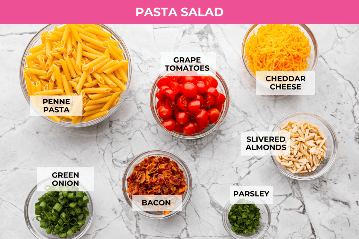 If there’s one side dish that disappears fast, it’s this million dollar pasta salad. It’s packed with crispy bacon, sharp cheddar, fresh veggies, and a creamy dressing that ties it all together. It’s sure to steal the spotlight at any table! Overhead shot of labeled million dollar pasta salad ingredients.