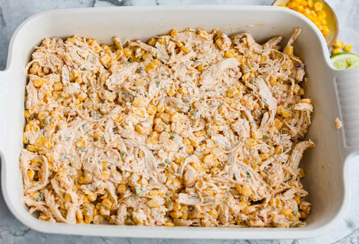 This Mexican Street Corn Chicken Casserole takes everything you love about elote, tangy lime, smoky Tajin, and creamy cotija, and turns it into one bubbly, cheesy weeknight dinner the whole family will devour! Everything added to a 9x13 baking dish ready to go into the oven.
