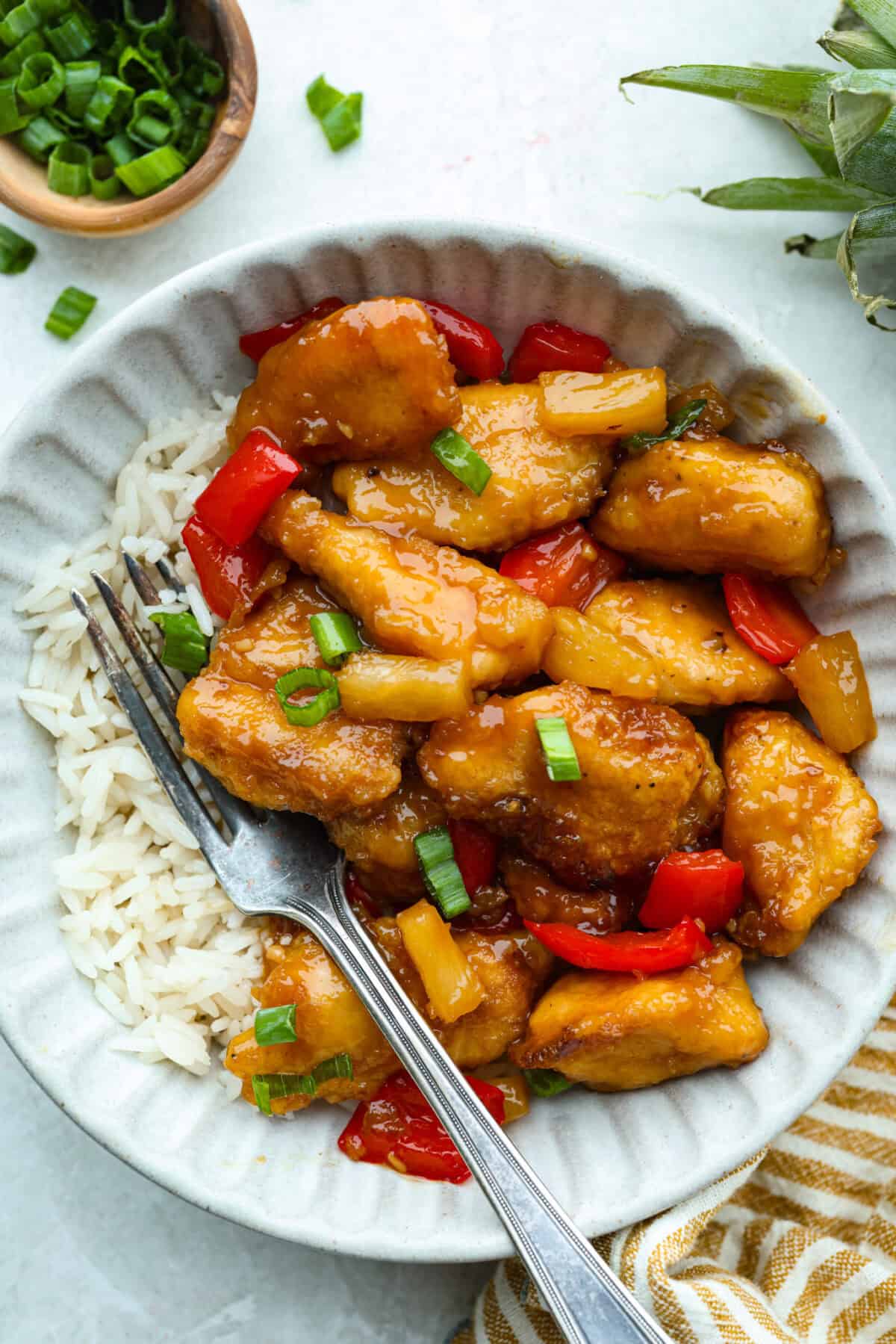 I'm updating my "Tuesday night dinner that feels like we're in Hawaii" with double the sauce! You guys asked, so I added more of that sweet, tangy, deliciousness to this Baked Sweet Hawaiian chicken! It's easy, even after a busy day! Serving of baked sweet Hawaiian chicken on a bed of rice.