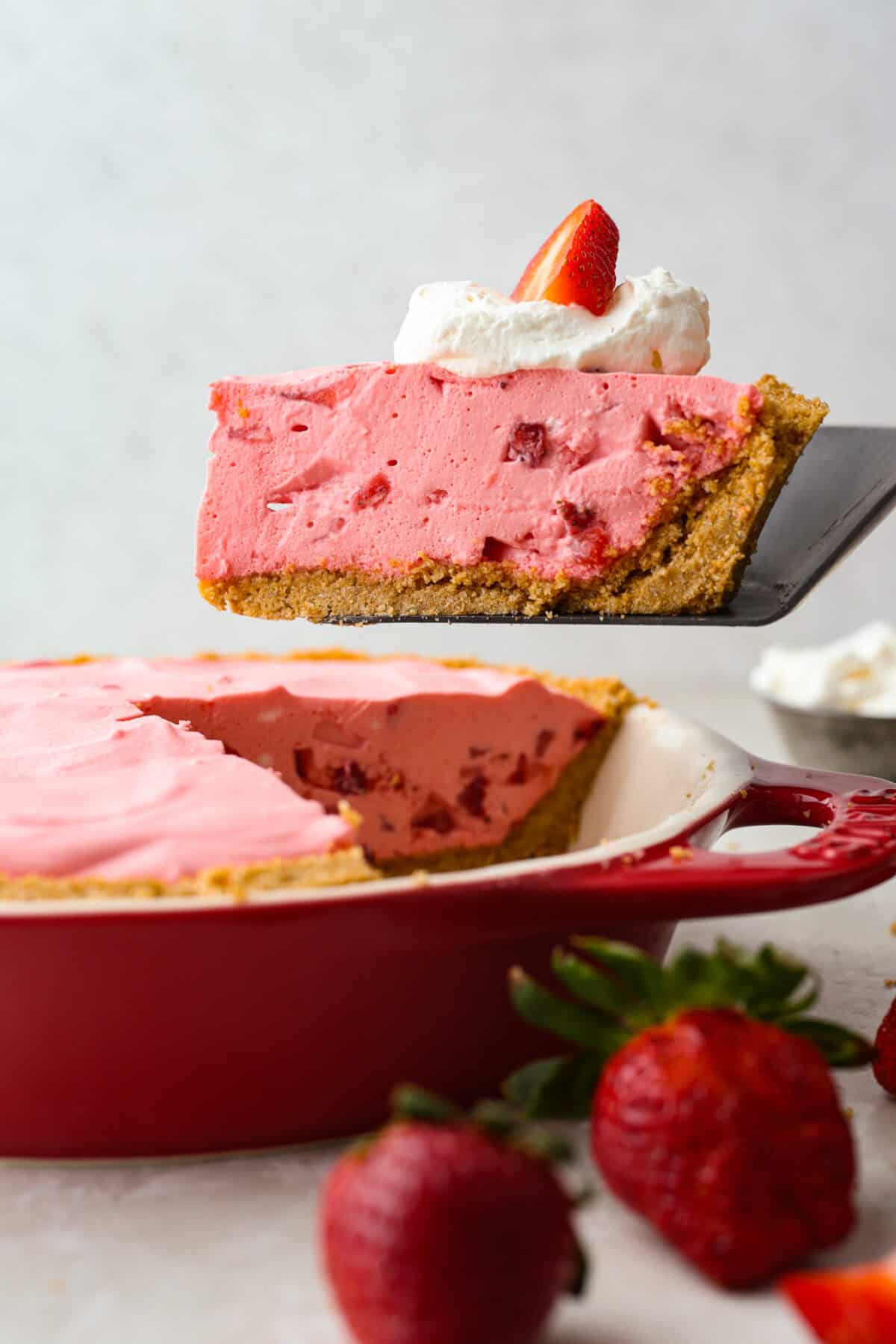 When itโs too hot to even think about turning on the oven, this no bake strawberry cream pie is exactly what you want waiting in the fridge. Itโs cool, creamy, loaded with fresh strawberries, and comes together without heating up your kitchen Someone lifting a slice of no bake strawberry cream pie from the pie pan.