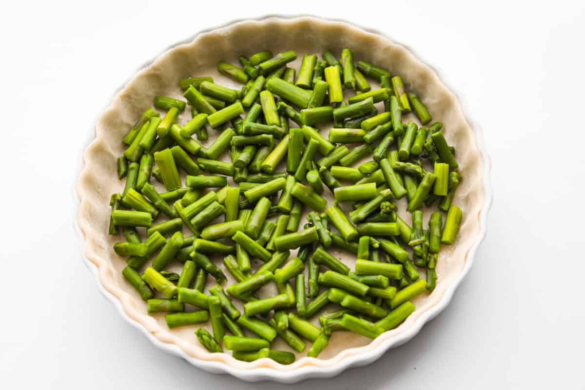 My asparagus quiche is one of those recipes I wait all year to make. Itโs creamy, cheesy, and those bright green asparagus pieces make every slice feel fresh and so good. Itโs simple, itโs pretty, and I love making it for a spring brunch! Cooked asparagus in the bottom of the pie crust.