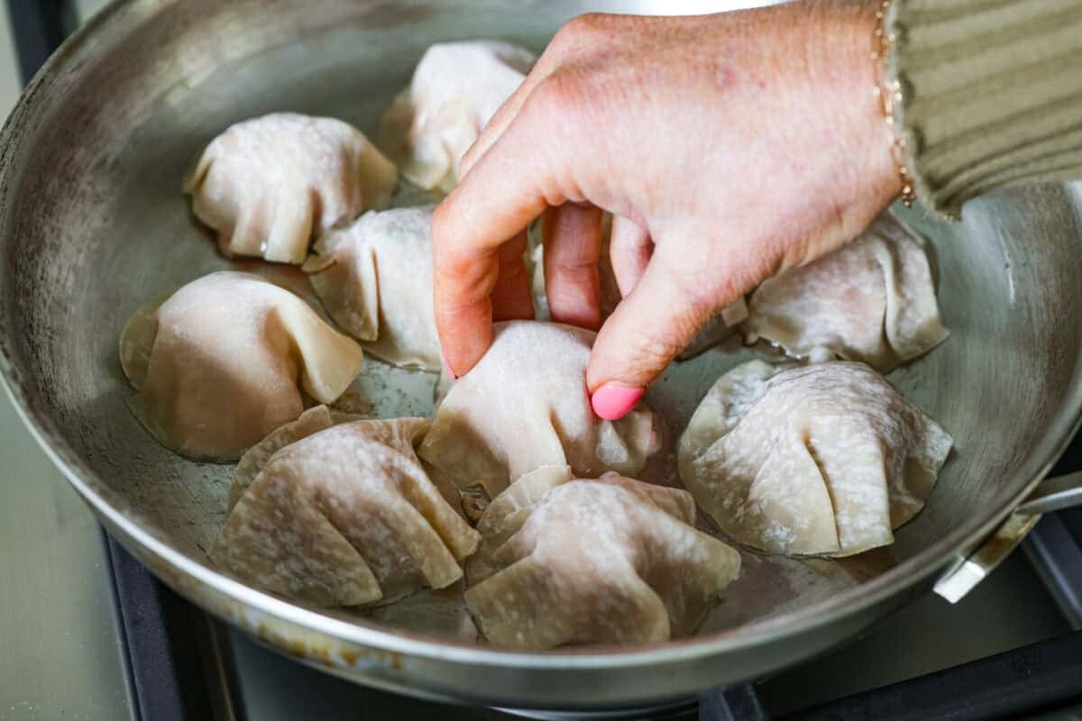 Blanket dumplings are a viral dumpling hack where you cook the filling and press the wrappers right on top. They are the ultimate shortcut to homemade dumplings, ready in just 30 minutes! Trust me, you will want to make these! Someone placing wonton wrappers on top of the meatballs in the skillet.