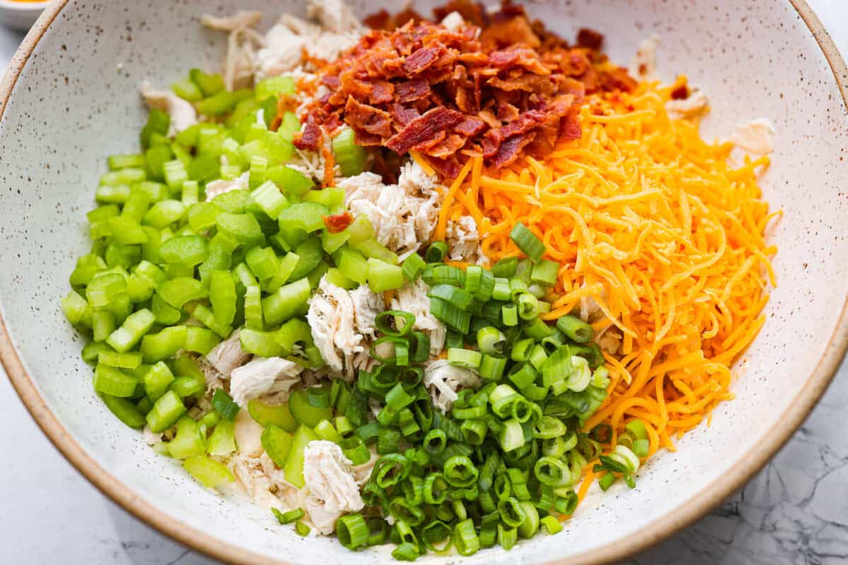 This crack chicken salad has no business being this good! Itโs creamy, packed with ranch, bacon, and cheddar, and disappears way too fast. Pile it on a croissant or eat it straight from the bowl. I promise I won't judge! Cheese, bacon, chicken, celery, and green onions added to the sauce mixture.