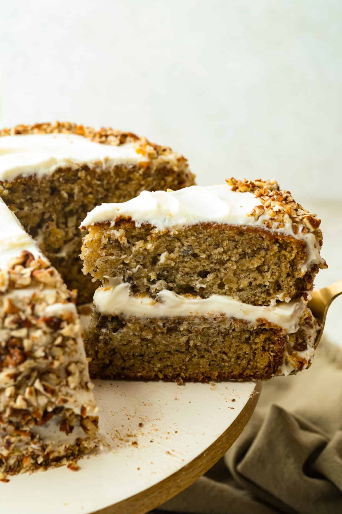 If you’ve never had hummingbird cake, just know it’s one of those cakes people take a bite of and immediately ask for the recipe. It’s soft, sweet, packed with banana and pineapple, and topped with a cream cheese frosting that is to die for! Slice of hummingbird cake being taken out of the cake.