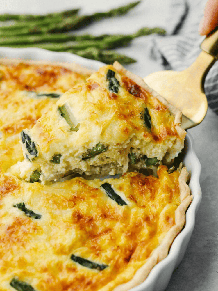 My asparagus quiche is one of those recipes I wait all year to make. Itโs creamy, cheesy, and those bright green asparagus pieces make every slice feel fresh and so good. Itโs simple, itโs pretty, and I love making it for a spring brunch! someone lifting out a slice of asparagus quiche.