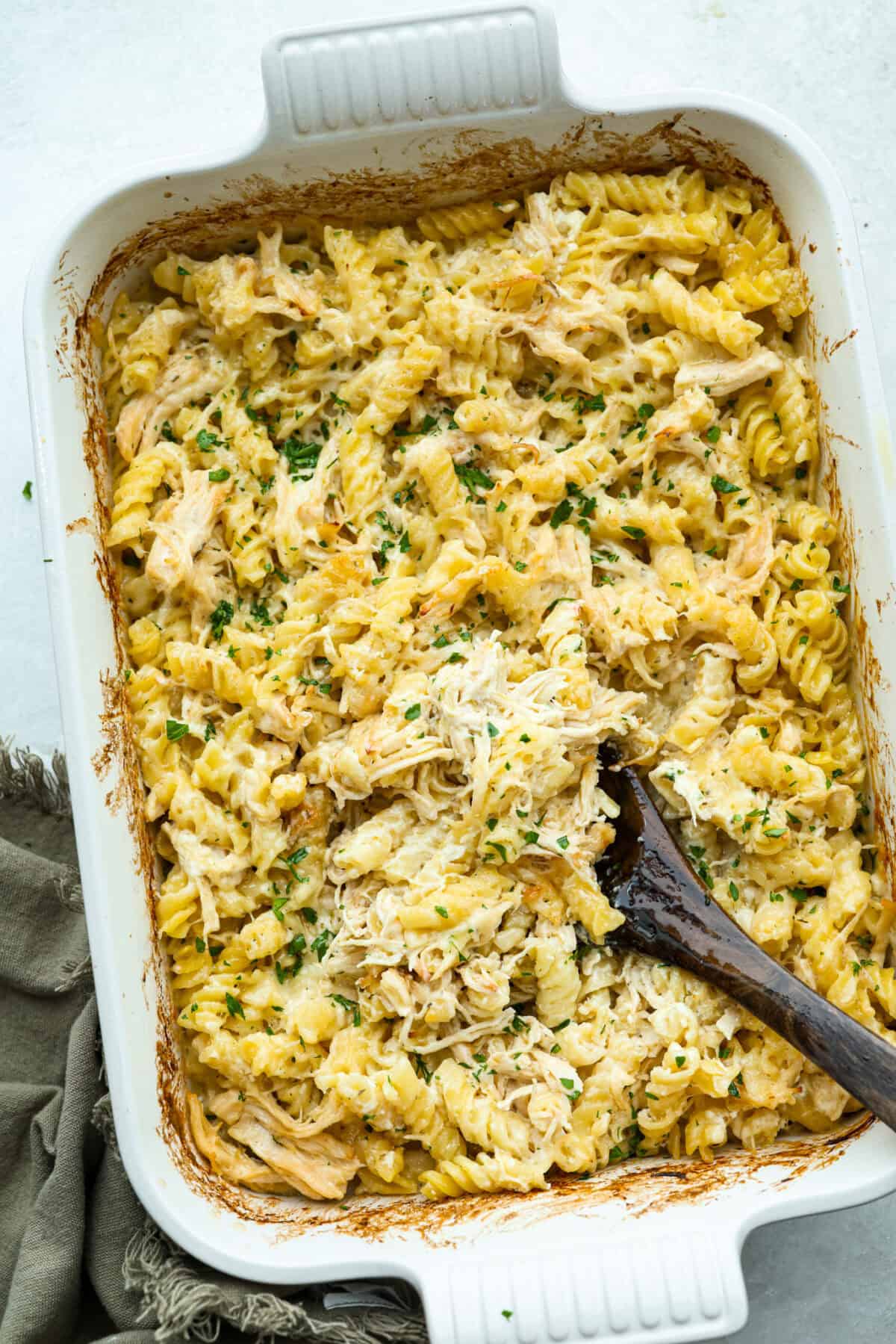 This baked Olive Garden chicken is pure comfort food made easy! It uses Olive Garden Italian dressing and just 5 other ingredients to create a creamy, cheesy pasta bake everyone loves. Quick prep, one dish, and big flavor in every bite! Overhead image of olive garden chicken bake in a baking dish.